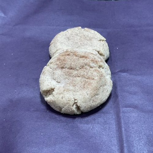 Two biscuits sitting on top of a purple cloth.