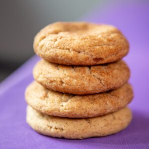 Stack of four round cookies on purple surface.