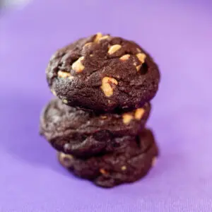 Stack of chocolate cookies on purple surface.