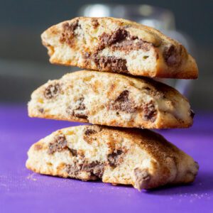 Stack of chocolate chip cookies on purple background.