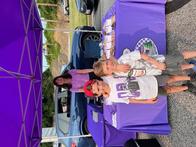 Two children standing next to a purple table.
