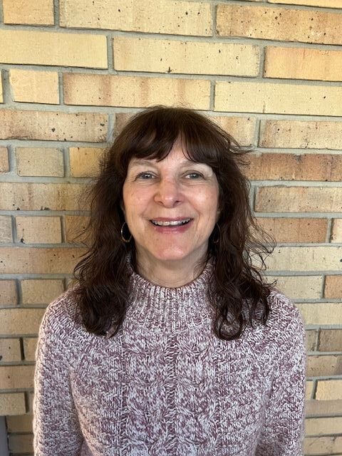 A woman standing in front of a brick wall.