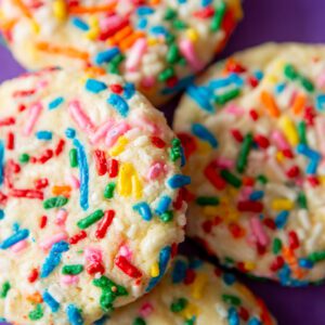 Colorful sprinkle cookies on a purple background.